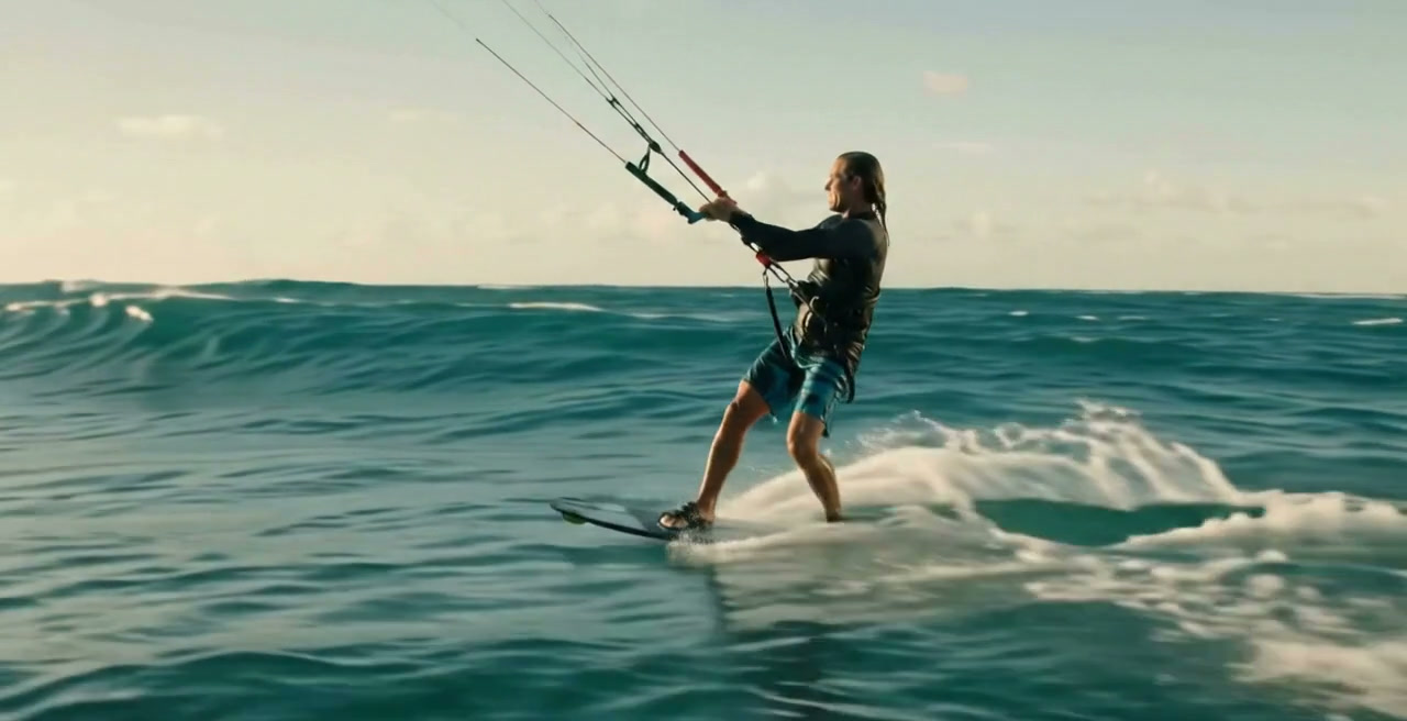 A kite surfer crossing open ocean under a low sun.
